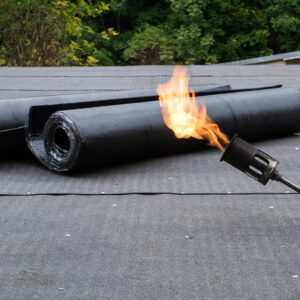 Heating and melting bitumen roofing felt Flat roof installation.